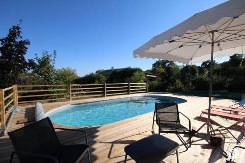 a swimming pool with two chairs and an umbrella at Tri-O-Bois in Thianges