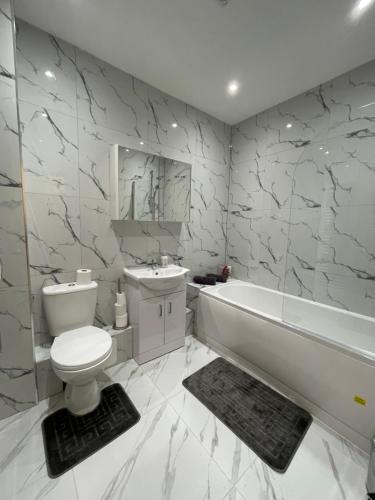 Flitwick Luxury 3 Bedroom Apartment في فليتويك: حمام مع مرحاض وحوض استحمام ومغسلة