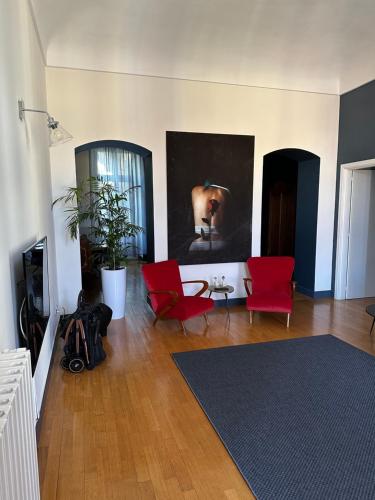 リヴォリにあるCasa Piolti Rivoliの赤い椅子と壁画のあるリビングルーム