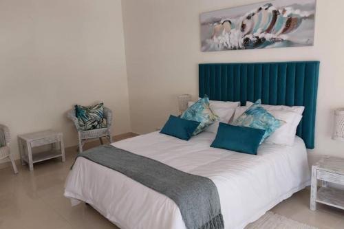 a bedroom with a large bed with a green headboard at Tropicana Guesthouse in Ponta do Ouro