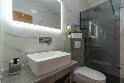 a white bathroom with a sink and a shower at Vila Snjezana in Trogir