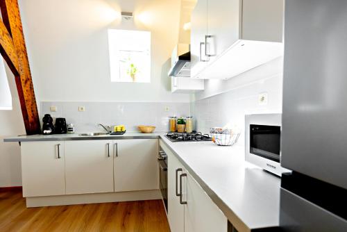 a white kitchen with white cabinets and a sink at Luxury Suites Stay in Antwerp