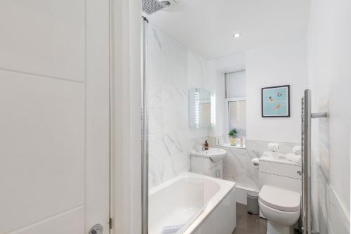 uma casa de banho branca com uma banheira e um WC em Coastal Chic Retreat in Central Brighton em Brighton & Hove
