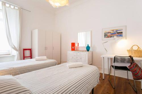 a bedroom with two beds and a desk and a desk at Principe Real Orange tree w/ view 3 bedrooms flat! in Lisbon