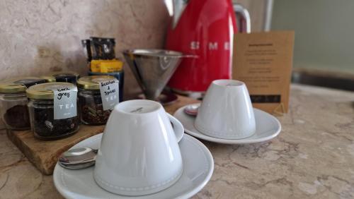 two white cups and saucers sitting on a counter at OnJ S. Lazaro Lisboa in Lisbon