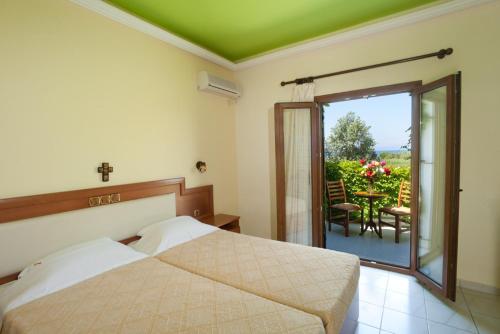 a bedroom with a bed and a balcony with a table and chairs at Castello Rosso Hotel in Nea Stira