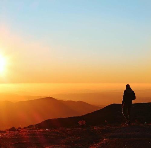 a person standing on top of a mountain looking at the sunset at Casa de São Lourenço - Burel Panorama Hotel - member of Design Hotels in Manteigas