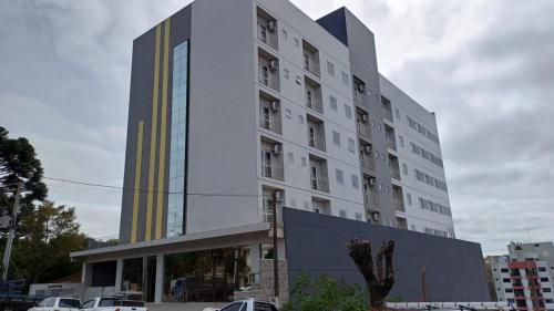 um edifício alto com carros estacionados em frente em HOTEL MAESTRO EXECUTIVE PATO BRANCO em Pato Branco