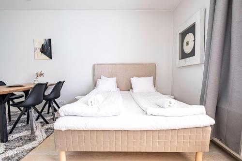 a bedroom with a bed with white sheets and a table at Nice studio apartment on a pedestrian street in Helsinki