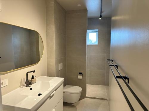 a bathroom with a sink and a toilet and a mirror at Urriðafoss Waterfall Villa in Selfoss