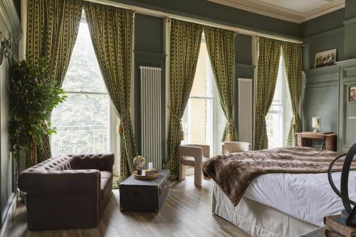 ein Schlafzimmer mit grünen Wänden, einem Bett und einem Stuhl in der Unterkunft 81 Promenade Studios in Cheltenham