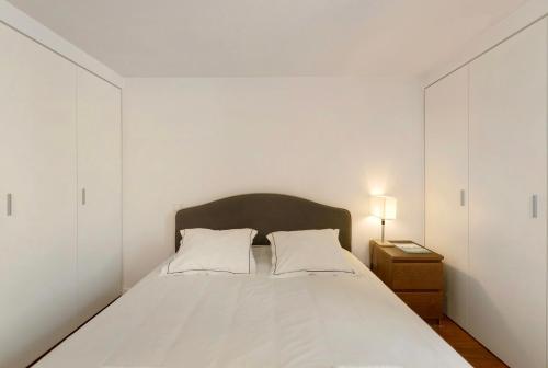 a white bedroom with a bed and a night stand at Estoril Close To The Sea in Estoril