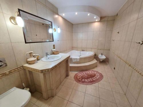 uma casa de banho com uma banheira, um lavatório e um WC. em Pensjonat SPA u Tomasza em Niechorze