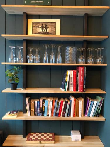a book shelf filled with glasses and books at Botanical garden apartments in Oslo