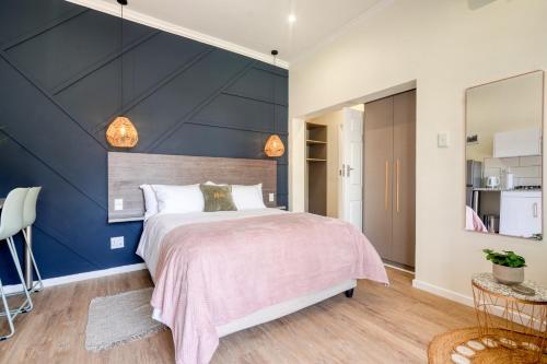 a bedroom with a large bed with a blue accent wall at Hampton Collection - 2 Sleeper Studio Apartment with Pool in Durban