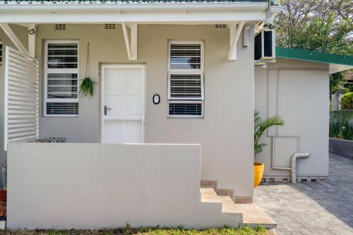 a white house with a white fence in front of it at Hampton Collection - 2 Sleeper Studio Apartment with Pool in Durban