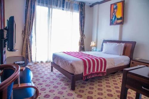 um quarto com uma cama e uma grande janela em Hotel Karisimbi em Kigali