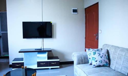 sala de estar con sofá y TV de pantalla plana en Sojah Apartment, en Dar es Salaam
