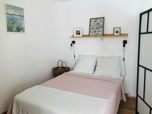 a bedroom with a bed with white sheets and a shelf at Superbe appartement avec internet et parking gratuit in Avignon