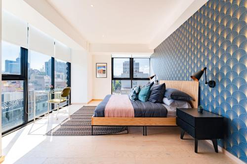 1 dormitorio con 1 cama con pared azul en NEW La Roma Penthouse 100m2 Terrace Pool and Gym en Ciudad de México