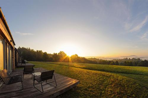 a deck with chairs and the sunset in the background at Widokowe Stodoły Bieszczady in Lesko