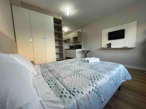 1 dormitorio con 1 cama con colcha blanca en Elegance PUC, en Porto Alegre