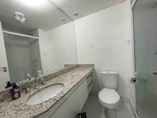 a bathroom with a sink and a toilet and a mirror at Elegance PUC in Porto Alegre