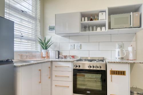 a kitchen with white cabinets and an oven at Hampton Collection - Contemporary 3 Sleeper Apartment with Pool in Durban