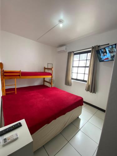 a small bedroom with a bed with a red blanket at Apartamento Marisco in Torres