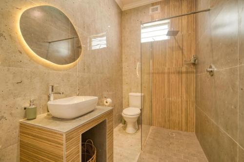a bathroom with a sink and a toilet and a mirror at Hampton Collection - Contemporary 3 Sleeper Apartment with Pool in Durban