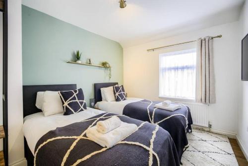 考文垂的住宿－LOW rate for a 4-Bedroom House in Coventry with Free Unlimited Wi-fi 2 Car Parking 53 QMC，蓝色和白色的客房内的两张床