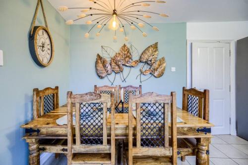 a dining room table with chairs and a clock on the wall at 4 Bedroom House in Coventry, Sleeps 10, Unlimited Wi-Fi, with Fireplace, Free Parking - 53QMC in Coventry