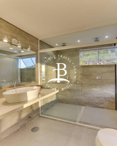 a bathroom with a tub and a sink and a mirror at Bangalo com jacuzzi vista mar e churrasqueira in Florianópolis