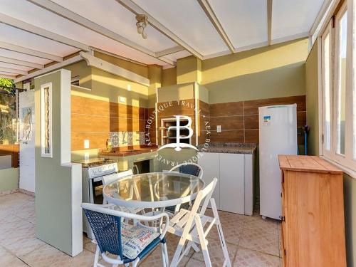 a kitchen with a glass table and some chairs at Bangalo com jacuzzi vista mar e churrasqueira in Florianópolis