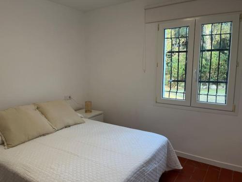 1 dormitorio con 1 cama blanca y 2 ventanas en Casa a la Costa Brava, en Calonge