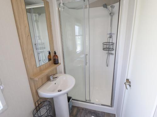 a white bathroom with a shower and a sink at 62 Pinewood in Mablethorpe