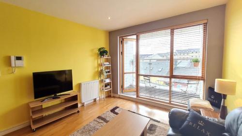 a living room with a flat screen tv and a large window at 12 Courthouse Square in Clifden