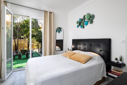 a bedroom with a large bed and a large window at Bord de mer- Studio avec jardin in Roquebrune-Cap-Martin