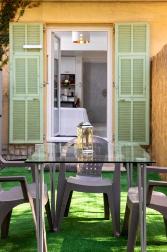 une table en verre et des chaises sur une pelouse avec une chambre dans l'établissement Bord de mer- Studio avec jardin, à Roquebrune-Cap-Martin