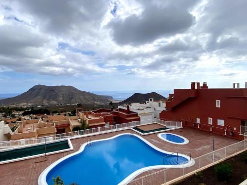 a resort with a large swimming pool and mountains in the background at Bonitos atardeceres sobre Los Cristianos in Chayofa