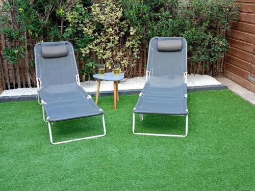 2 chaises et une table sur de l'herbe verte dans l'établissement Maison de vacances bord de mer, idéal famille ou groupe 8 pers, à Sérignan
