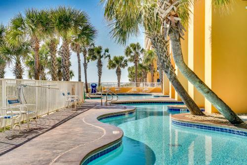 a swimming pool with palm trees in a resort at Splash Beach Resort by Panhandle Getaways in Panama City Beach