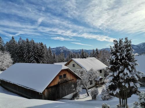a barn covered in snow with trees and mountains at Ferienhaus Zwickelreith in Göstling an der Ybbs