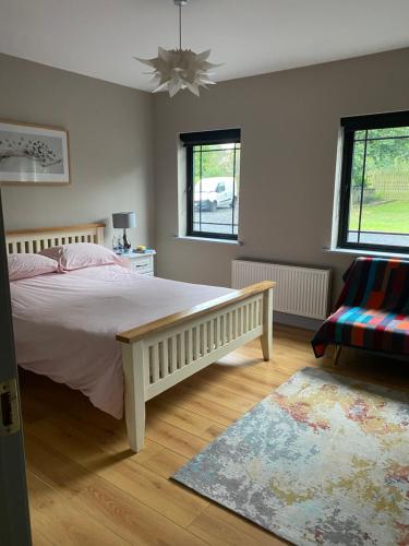 a bedroom with a bed and a couch and two windows at Room to rent in Mullingar