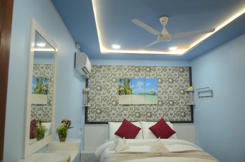 una camera da letto con letto, cuscini rossi e soffitto di Isle Inn Guesthouse a Fuvahmulah