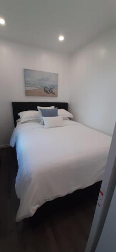 - un lit blanc avec des draps et des oreillers blancs dans l'établissement Stunning Modern Container Home on Golden Lake, à Killaloe Station