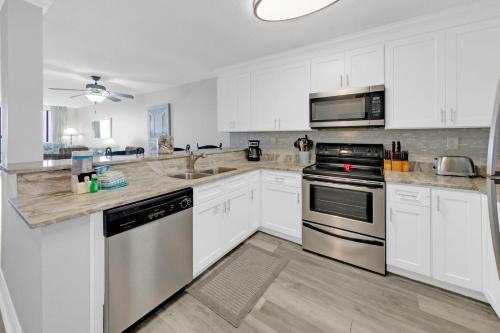 a kitchen with white cabinets and stainless steel appliances at Destin on the Gulf 404 - Amazing Views just Steps away from the Beach in Destin
