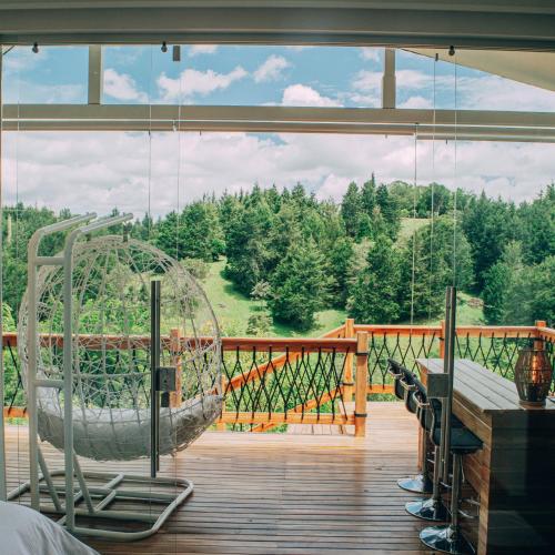 a balcony with a swing and a view of the woods at Örök Hotel in Rionegro