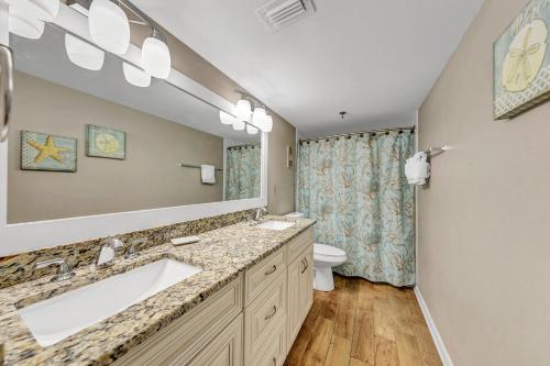 a bathroom with a sink and a toilet and a mirror at Destin on the Gulf 702 - Directly on the beach seventh floor with the best views in Destin