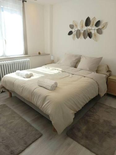 une chambre avec un grand lit avec des draps blancs dans l'établissement Appartement Les Géraniums, à Remiremont